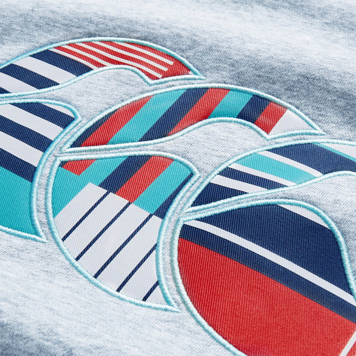 Close-up of a fabric design featuring three overlapping wave shapes with colorful striped patterns in red, teal, navy, and white—evoking the bold rugby-inspired style seen in the Canterbury Uglies Logo Hoodie by Canterbury.