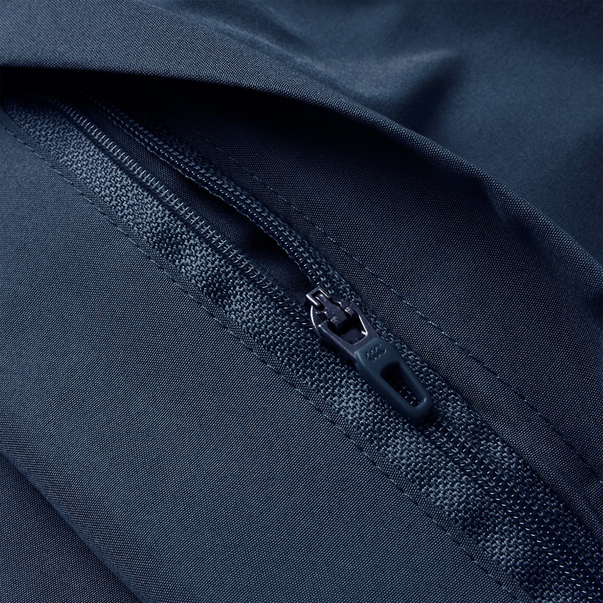 Close-up of a black zipper on dark navy fabric with detailed stitching, highlighting the quality of Canterbury Uglies 32" Stadium Pant by Canterbury—rugby-inspired athletic pants crafted for performance and durability.