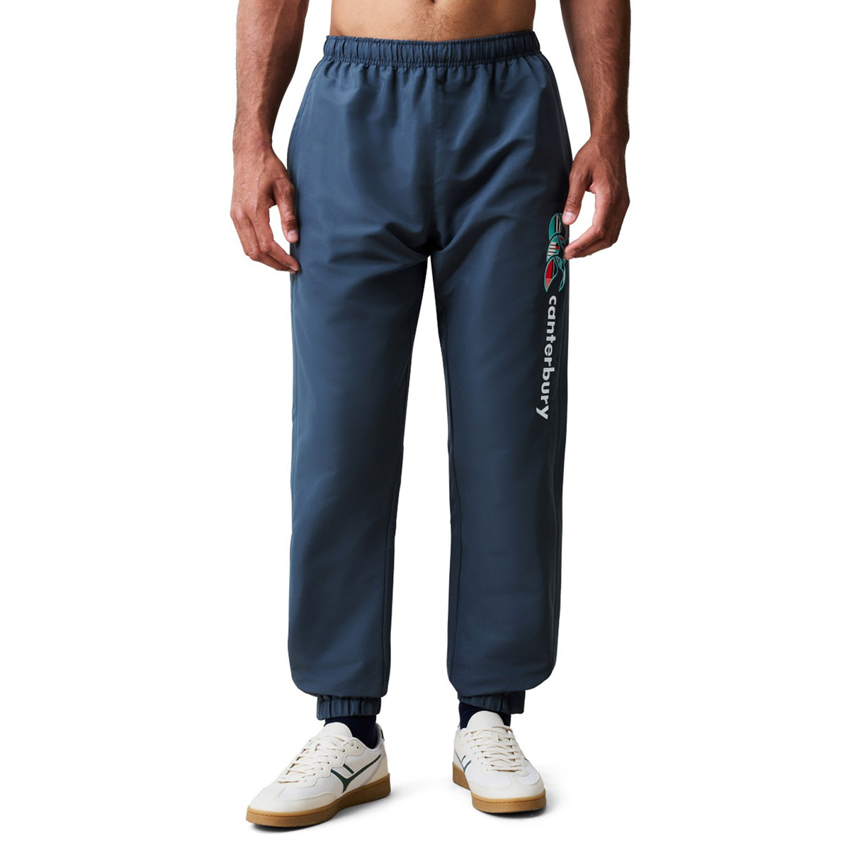 A person models the Canterbury Uglies 32" Stadium Pant with "Canterbury" text and logo on the left thigh, paired with white sneakers, against a plain background—ideal for fans of versatile rugby pants.