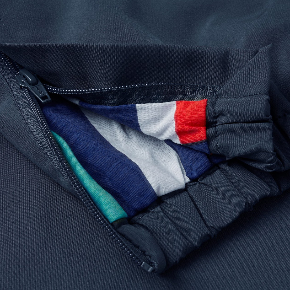 A close-up of a zippered pocket on the Canterbury Uglies 32" Stadium Pant reveals colorful striped fabric inside, showcasing the unique style of these athletic pants by Canterbury.