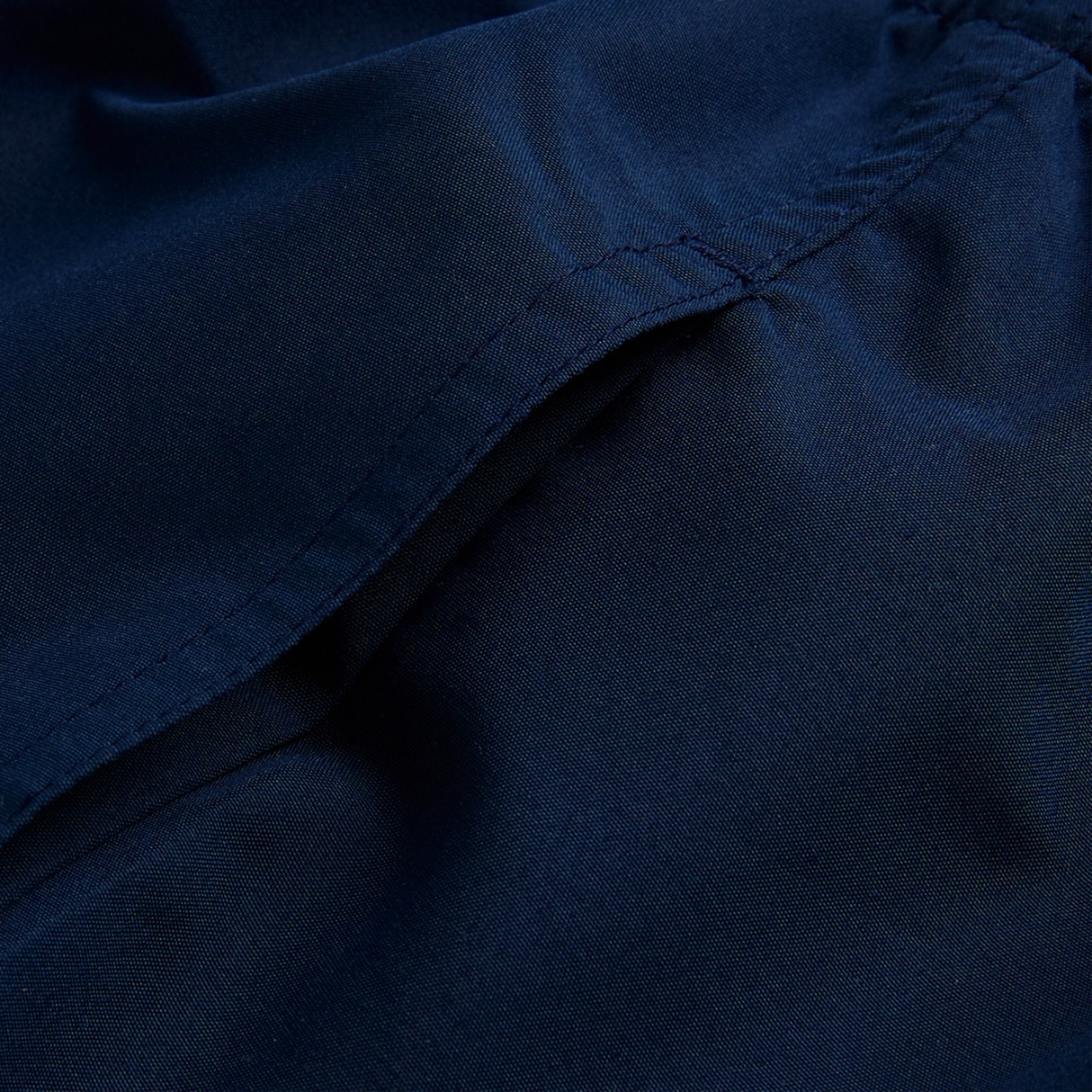 Close-up view of navy blue fabric with visible stitching and a seam, part of the Women's Canterbury Uglies Tactic Short by Canterbury.
