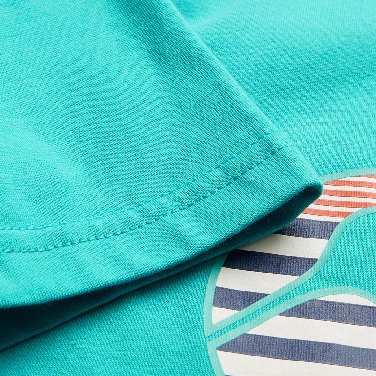 Close-up of a turquoise sleeve from the Canterbury Youth Canterbury Uglies Logo T-shirt, highlighting the fabric texture and stitching details over part of its colorful striped graphic, echoing the bold patterns distinctive to Canterbury's Uglies collection.