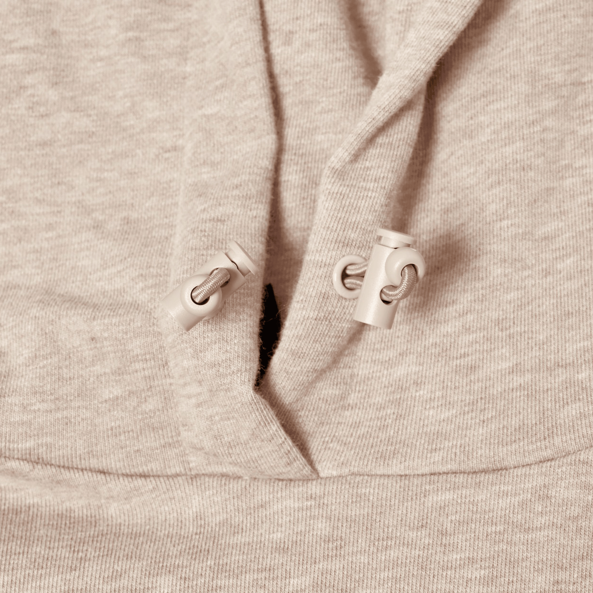 Close-up of Canterbury FORCE HOODIE in beige, highlighting the athletic fabric and two adjustable drawstrings with plastic toggles near the neckline.