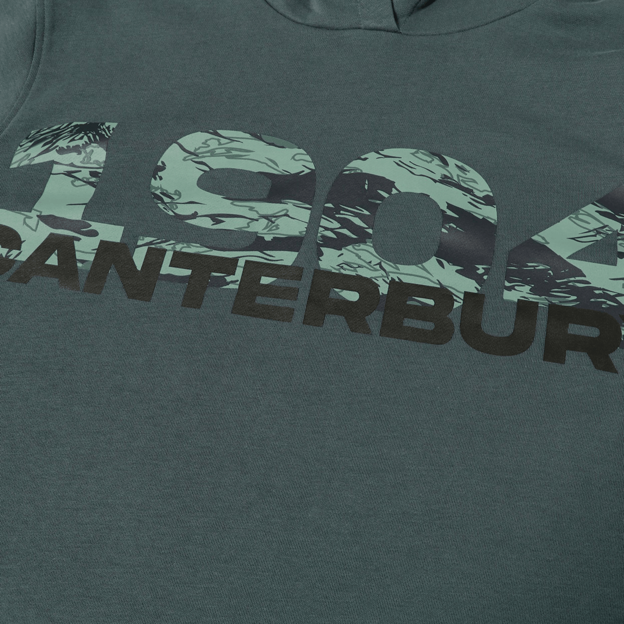 A teal shirt featuring "1904" in a green camo pattern and "CANTERBURY" in bold black below, perfect to pair with your Canterbury FORCE HOODIE.