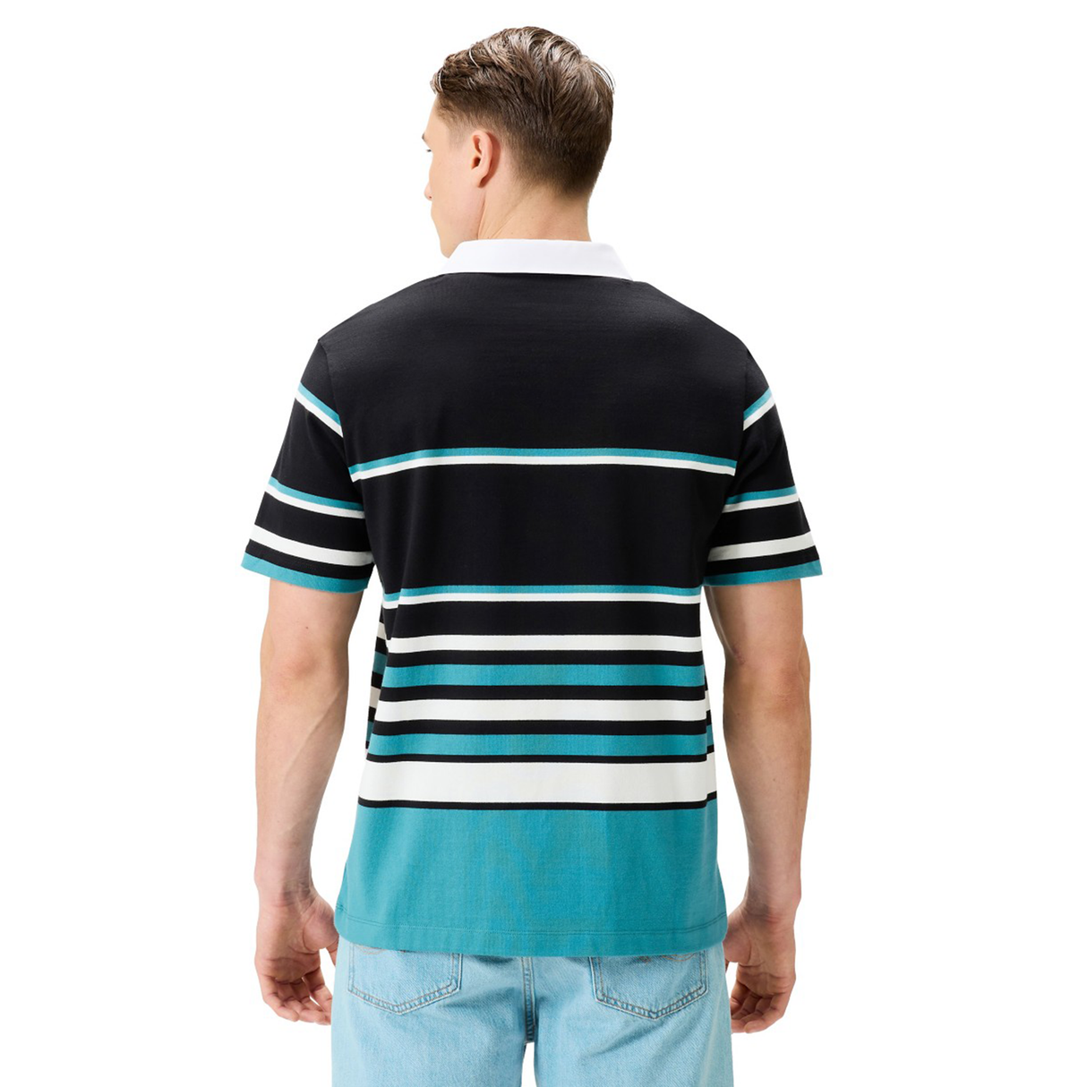 A man with short hair, shown from the back, wears a Canterbury Uglies Short Sleeve Classic Rugby Jersey—a black, teal, and white heavyweight cotton shirt by Canterbury—and light blue jeans.