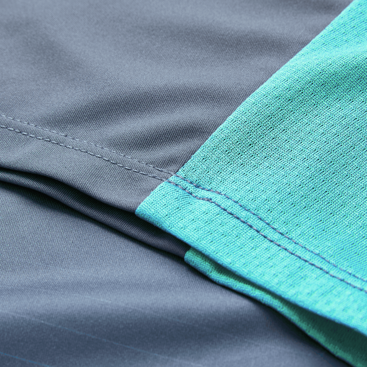 Close-up of detailed stitching on the Ireland 26/27 Summer Tour Superlight Training Tee by Canterbury, showing overlapping light blue and gray fabric sections.