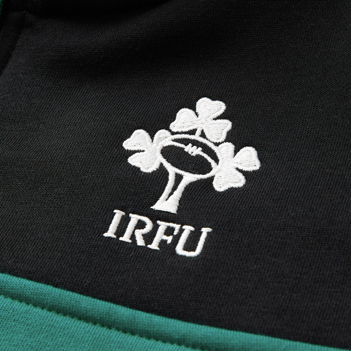 Close-up of an embroidered logo featuring a rugby ball with three shamrocks above the letters “IRFU” on black and green fabric, highlighting the quality craftsmanship of the Women’s Ireland 26 Legends 1/4 Zip Sweatshirt by Canterbury.