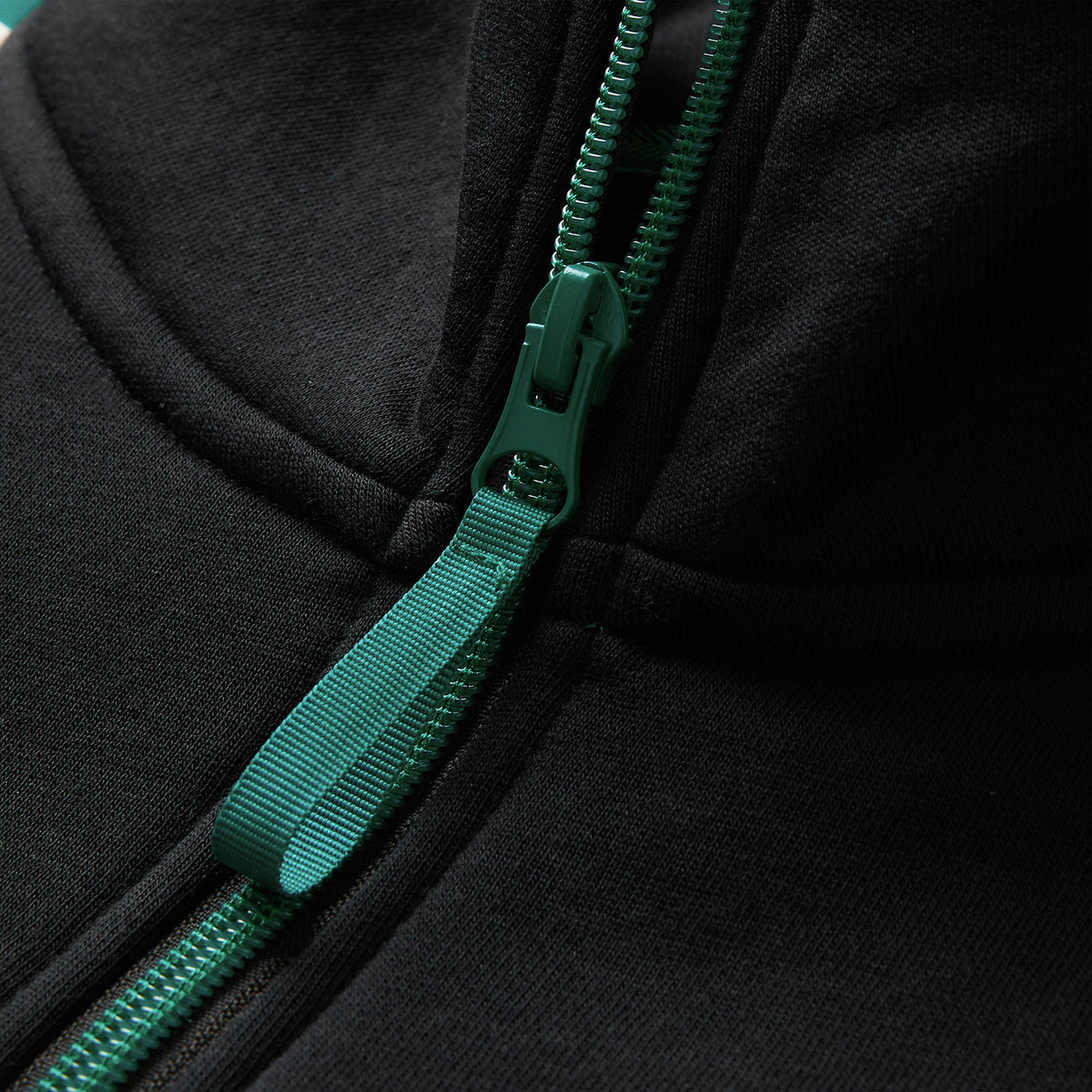 Close-up of a green zipper with a matching fabric pull tab on the Canterbury Women’s Ireland 26 Legends 1/4 Zip Sweatshirt, inspired by the classic Ireland Rugby sweatshirt.