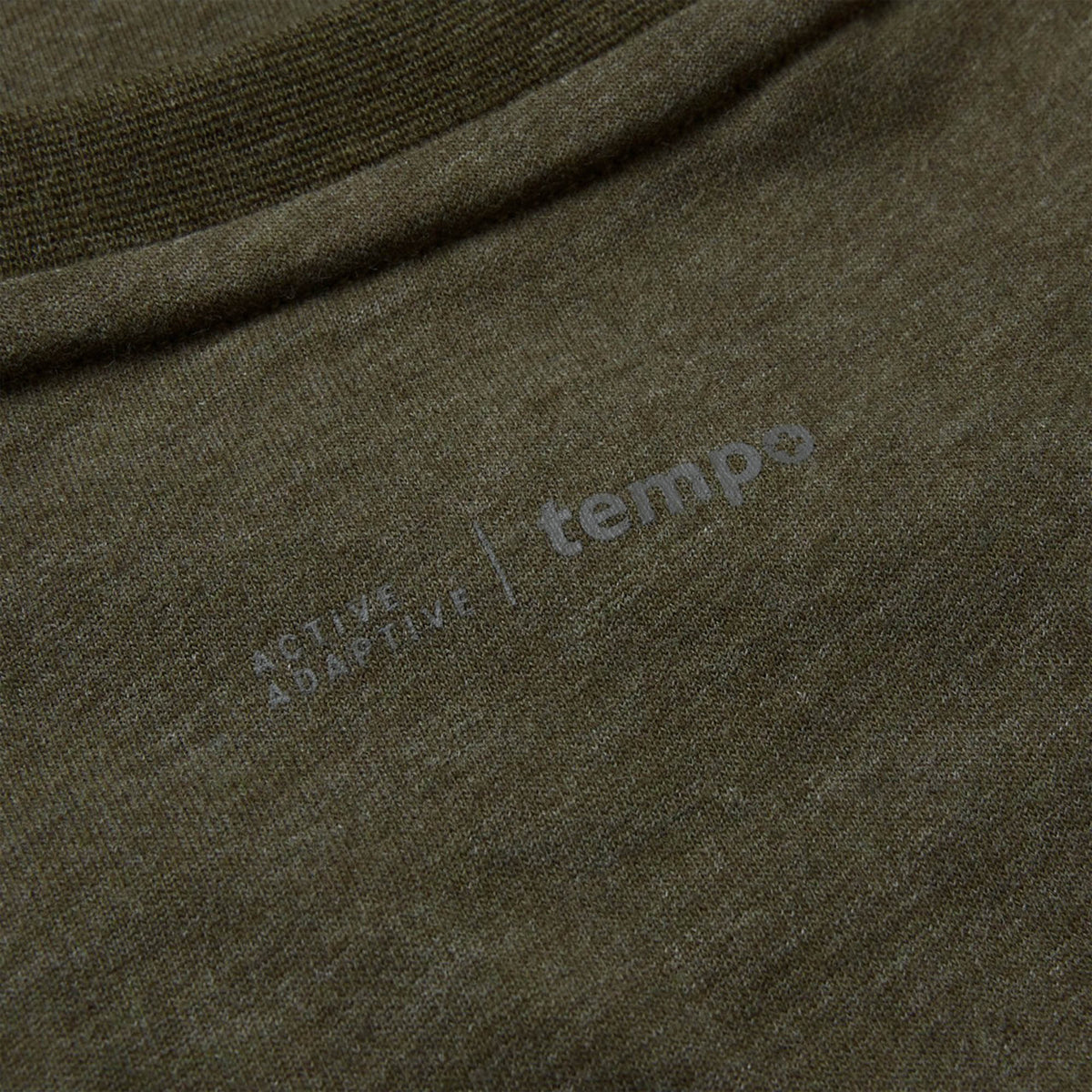 Close-up of an olive green Canterbury Tempo+ GFX Training T-Shirt fabric with faint printed text that reads “ACTIVE ADAPTIVE | tempo” near a seam, highlighting the quality and attention to detail in this Canterbury rugby training top.