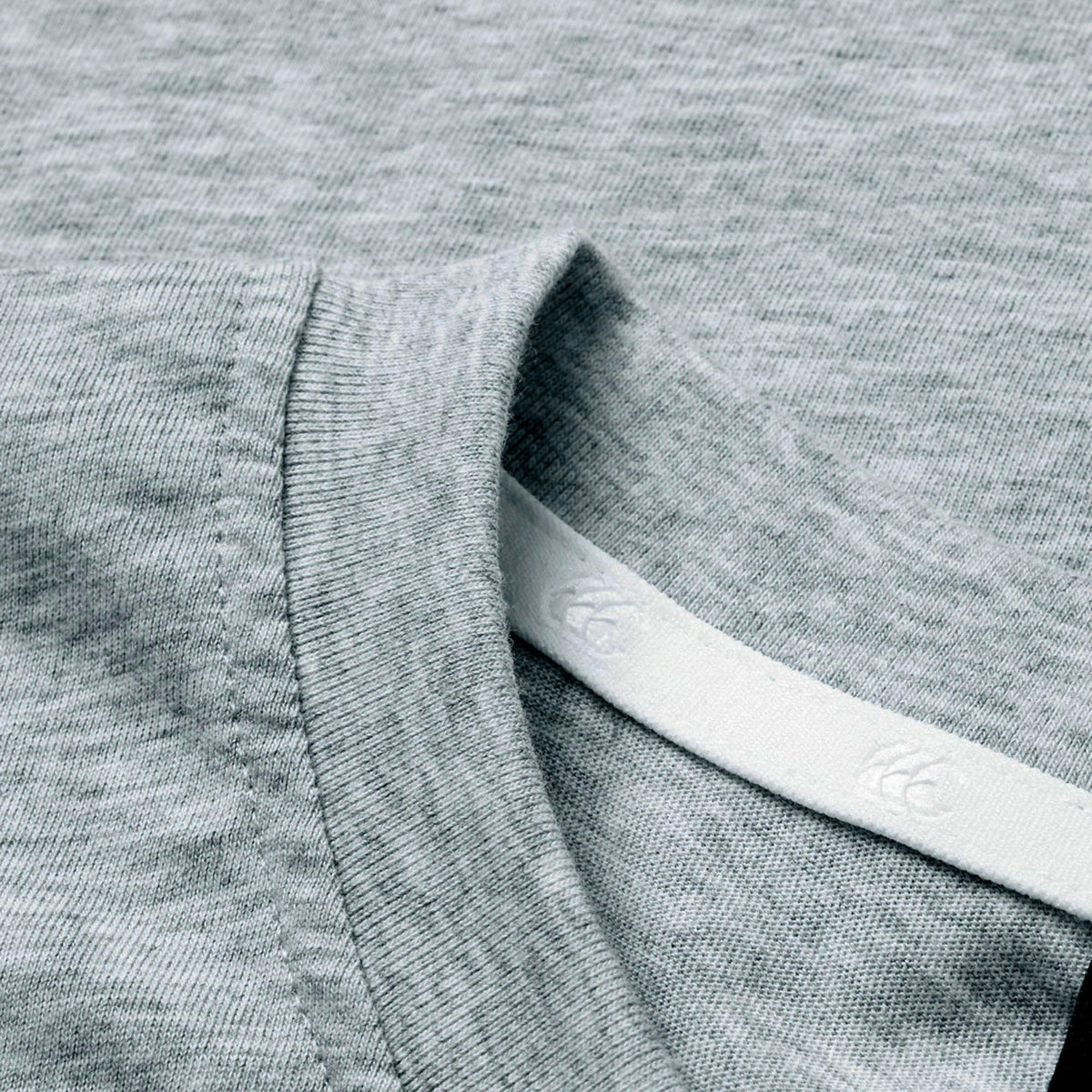 Close-up of the light grey heathered collar on the Canterbury Rakaia 2.0 T-shirt, featuring visible stitching and a white tag partially tucked inside the neckline—a fine example of classic New Zealand rugby apparel from Canterbury.