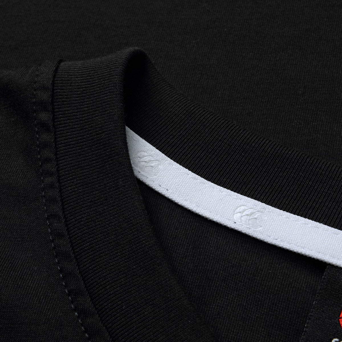 Close-up of the Canterbury Rakaia 2.0 T-shirt in black, featuring a detailed view of the collar with its white interior neckline strip, embossed pattern, and visible stitching—showcasing Canterbury’s renowned craftsmanship in New Zealand rugby apparel.