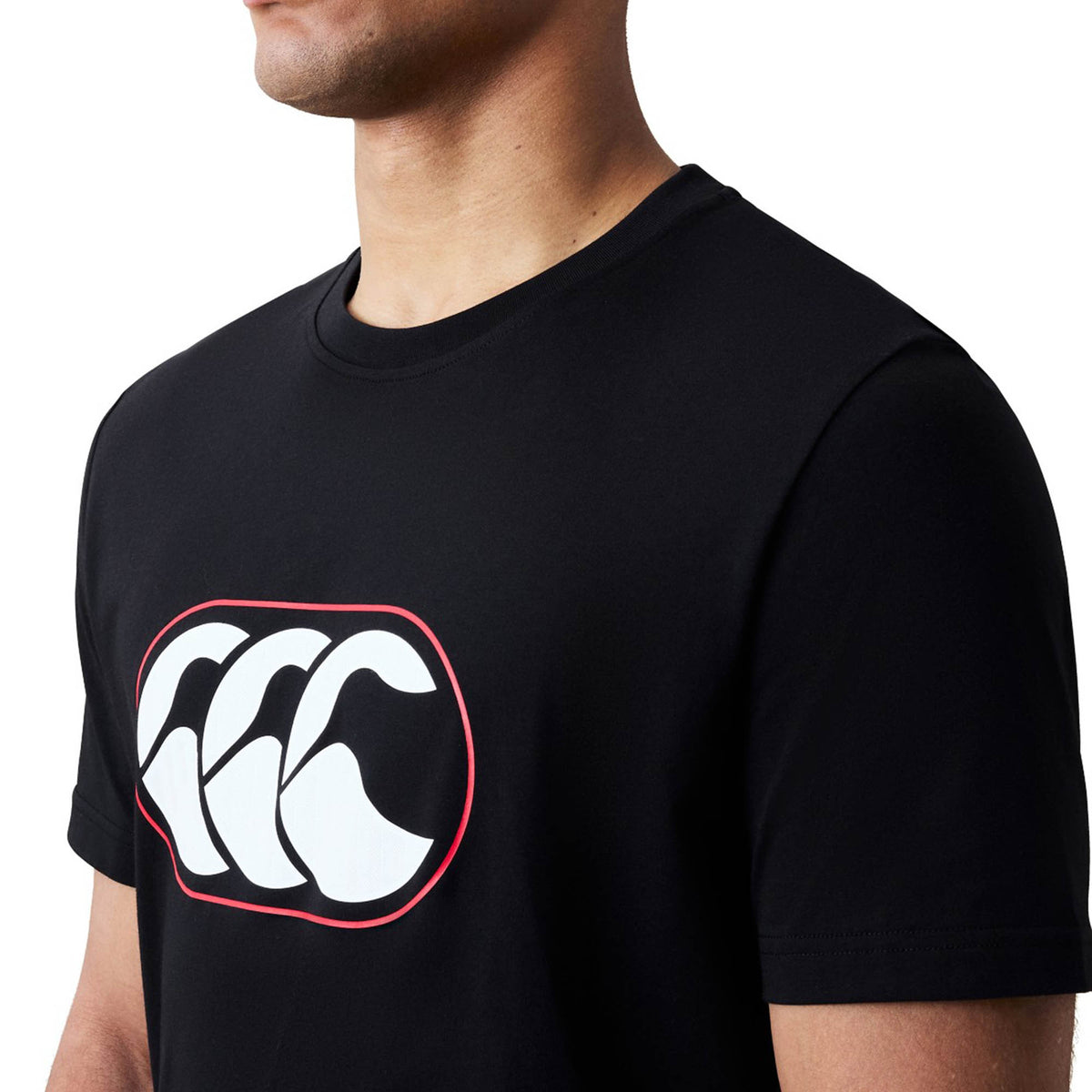 A person wearing the Canterbury Rakaia 2.0 T-shirt by Canterbury, featuring a black design with a white and red CCC logo on the chest and shown from shoulders to mid-torso, perfectly embodies classic New Zealand rugby apparel.