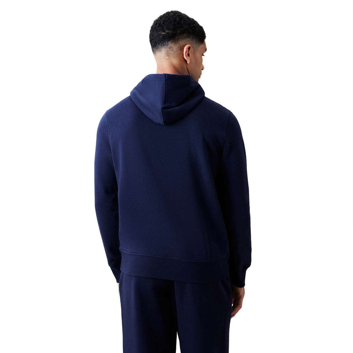 A man stands facing away from the camera, wearing a navy blue Canterbury Rakaia 2.0 Hoodie and matching pants against a plain white background.