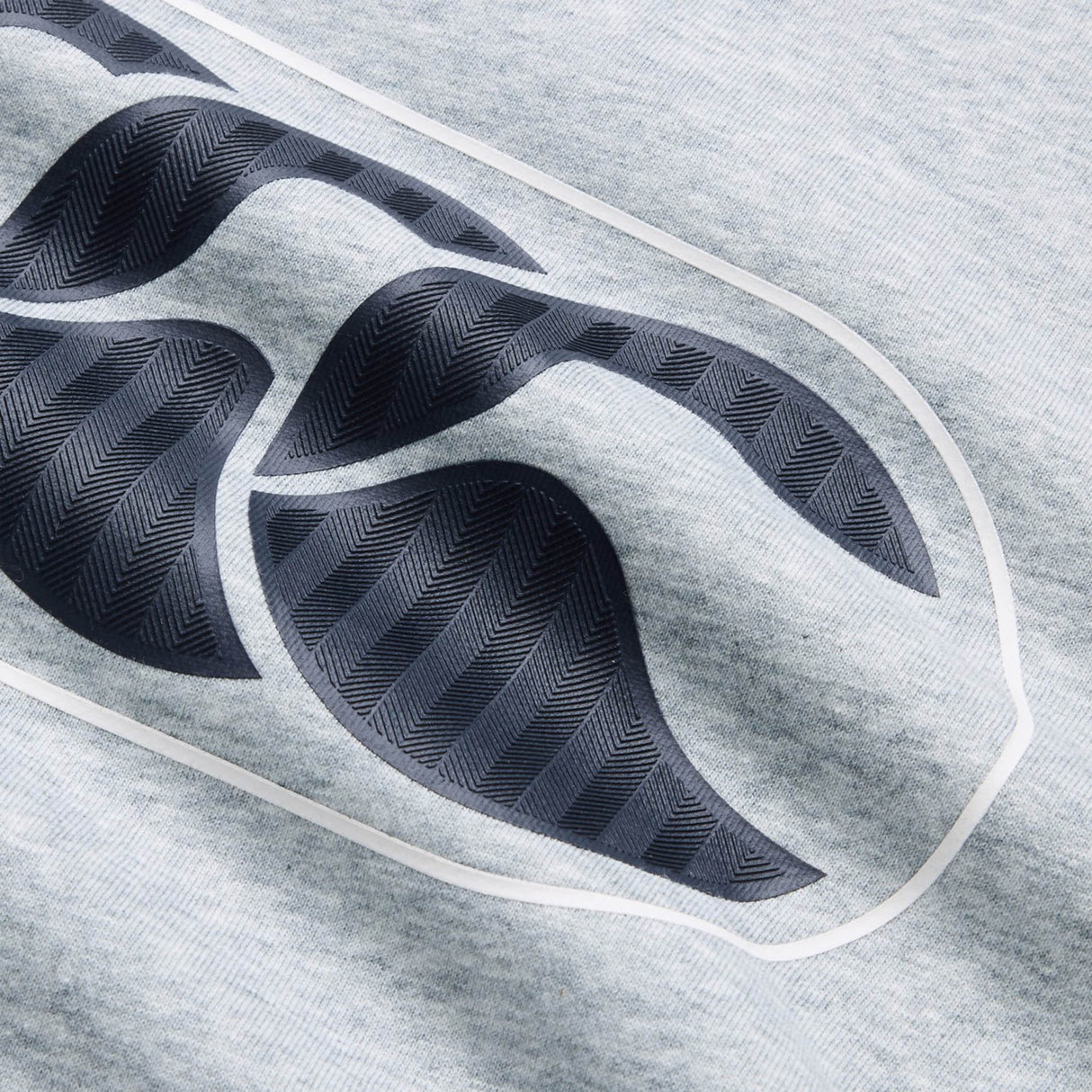 Close-up of a black textured abstract design outlined in white on light gray fabric—an eye-catching detail featured on the Canterbury Rakaia 2.0 Hoodie, a standout piece from Canterbury.