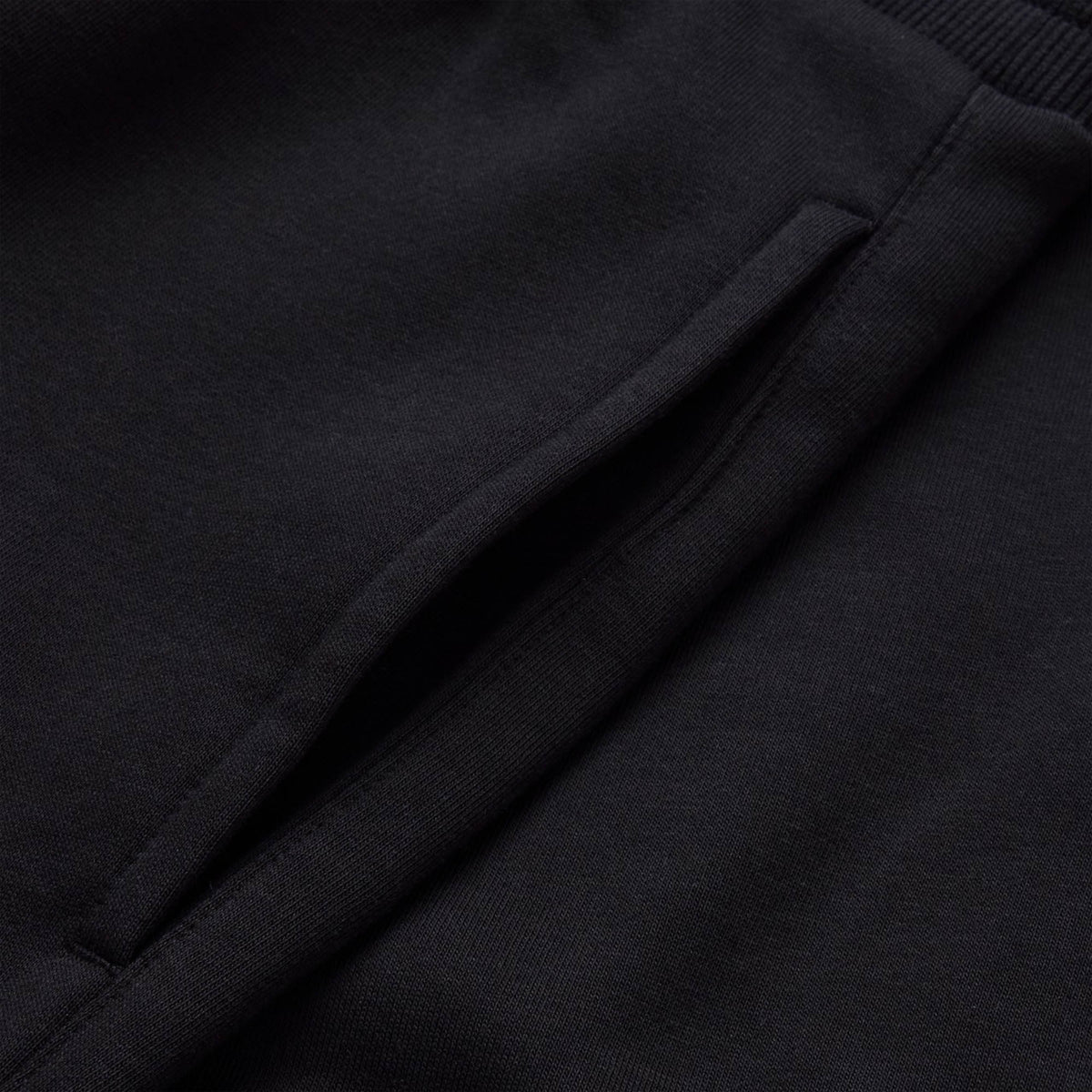 Close-up of a black fabric garment showing a slanted pocket opening, featured on Canterbury Rakaia 2.0 Fleece Pant by Canterbury.