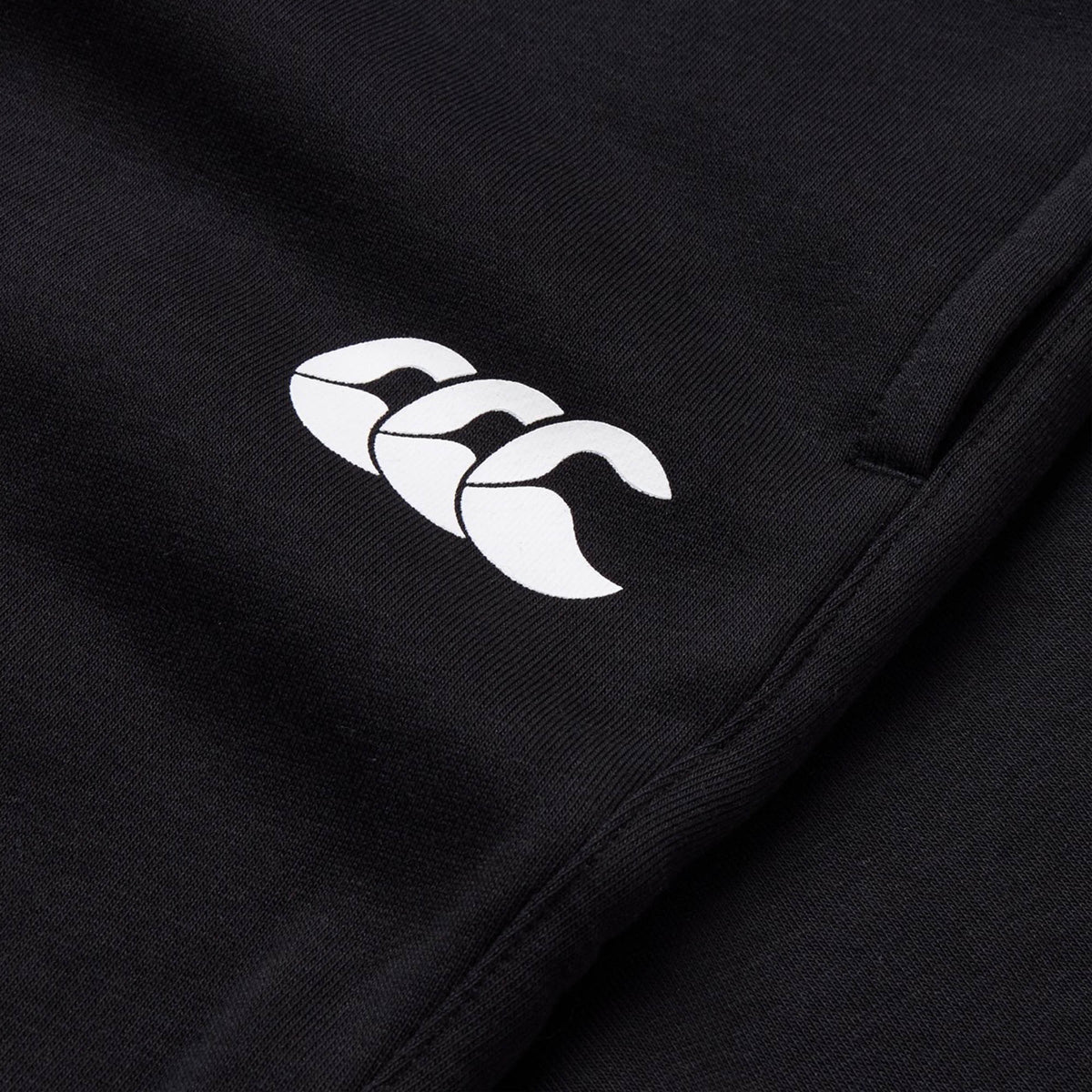 Close-up of the Canterbury Rakaia 2.0 Fleece Pant in black, showcasing the white Canterbury logo with three stylized overlapping “C” shapes.