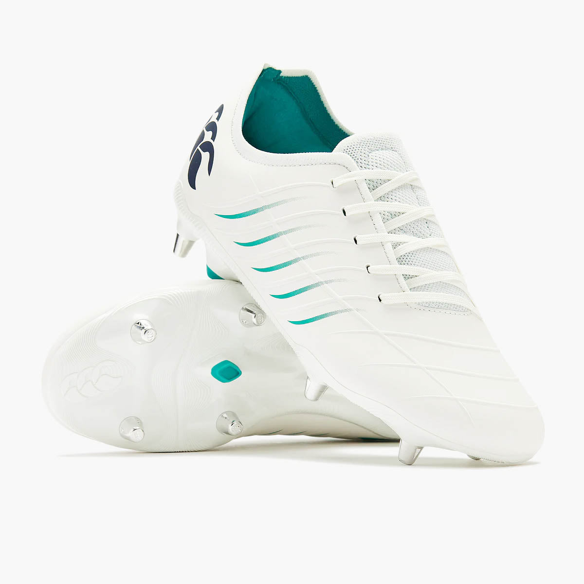 A pair of Canterbury Phoenix 2.0 Pro SG rugby boots in White/Baltic Green features striking teal accents and metal studs, with one boot standing upright and the other lying on its side to display the sole—ideal as soft ground rugby boots for players seeking reliable performance.
