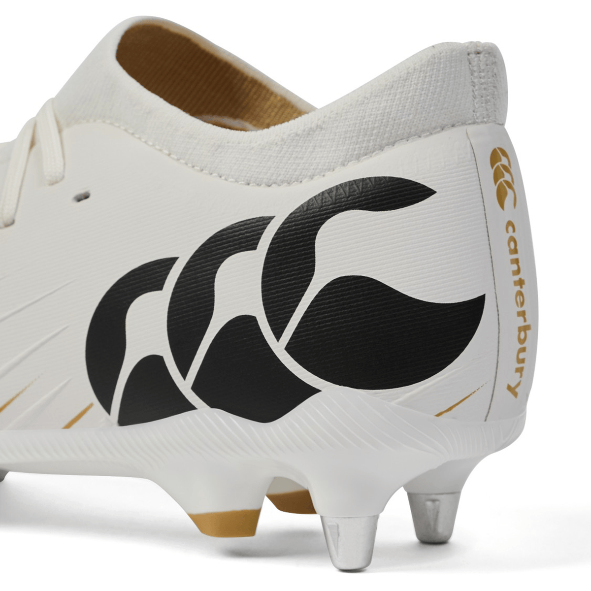 Close-up of the Canterbury Speed Falcon Pro SG - White, a lightweight rugby boot with black Canterbury logo and gold branding on the heel, featuring metal studs for optimal soft ground performance.