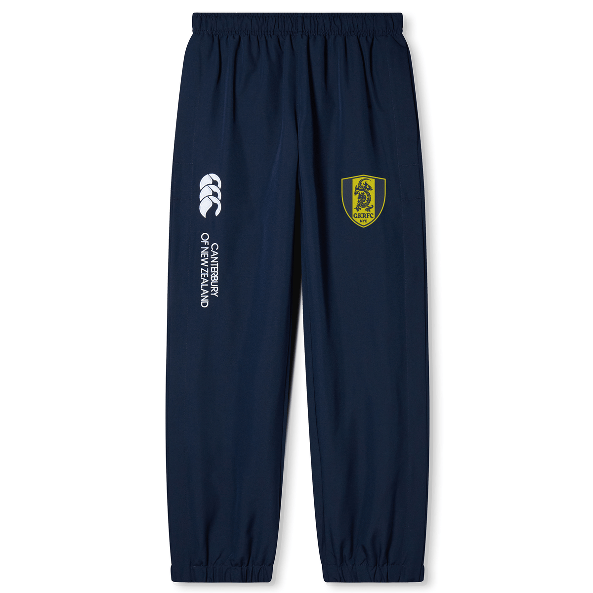 The Gotham Knights Cuffed Hem Stadium Pant by Canterbury, available from EMB Canterbury, are navy blue track pants featuring an elastic waistband and cuffed hem. They boast a logo with a yellow shield and lion on the left leg, as well as "Canterbury of New Zealand" text alongside the Canterbury logo on the right leg. Perfect for rugby enthusiasts.