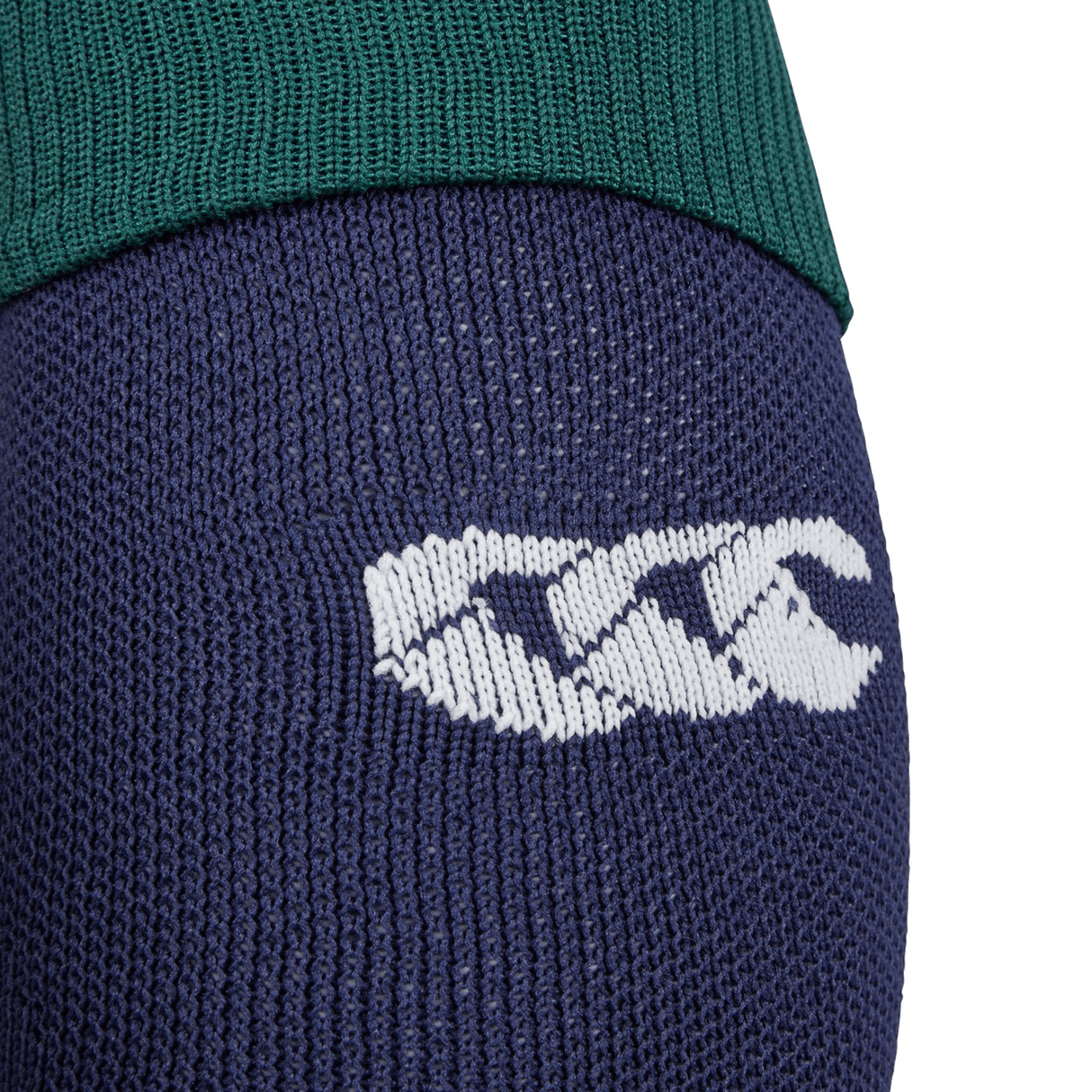 A detailed view of blue fabric featuring a white embroidered logo with three stylized, overlapping V shapes is situated below a green fabric section, echoing the precision seen in Canterbury's British & Irish Lions 25 Match Socks.