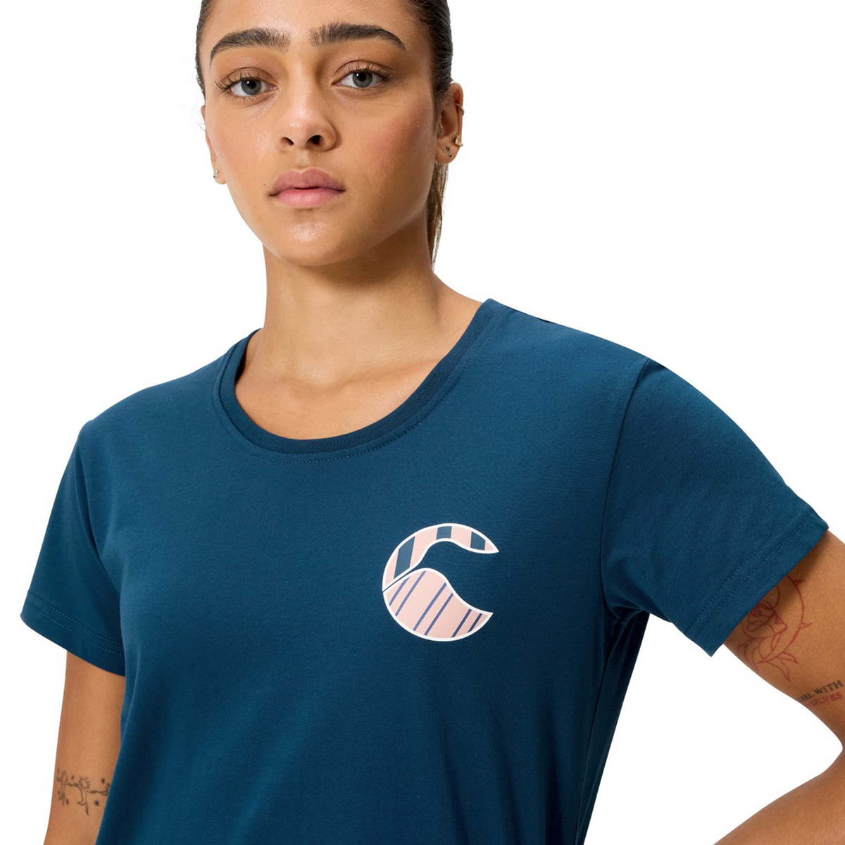 A woman faces the camera in a neutral pose, wearing the Canterbury Women's Uglies Logo T-Shirt with a bold "C" logo on the chest, highlighting this rugby-inspired women's apparel from Canterbury.