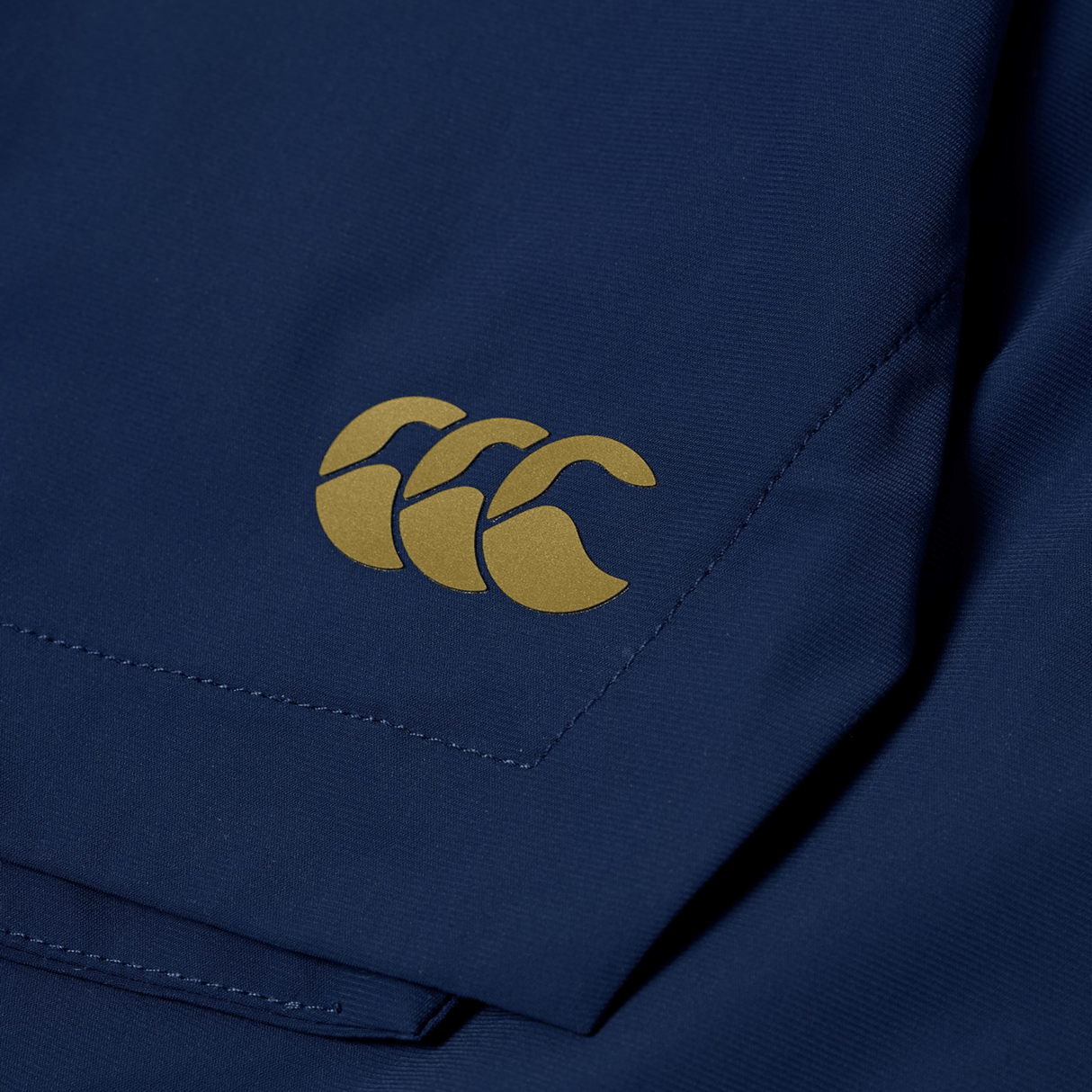 Close-up of the Canterbury Everest Woven Short 5" in navy blue, featuring a gold Canterbury logo on the corner and made from breathable wicking fabric.