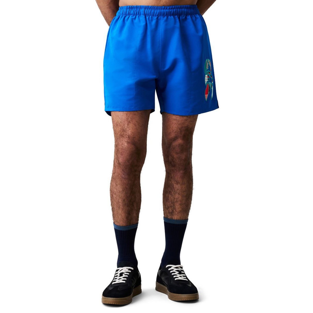 A person wearing Canterbury Uglies Tactic Short in bright blue, black socks, and black sneakers stands against a plain white background.