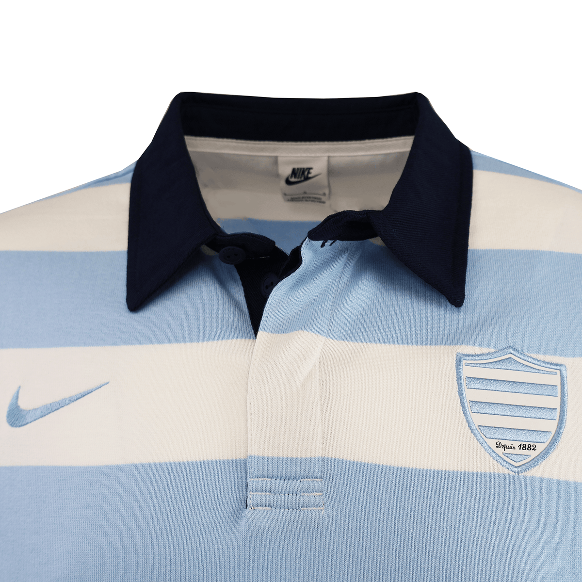 The Racing 92 25/26 Heritage Long Sleeve Rugby Jersey by Nike features light blue and white stripes, a navy collar, Nike logo on the right, and a shield emblem reading "Since 1882"—a classic, tradition-inspired piece.
