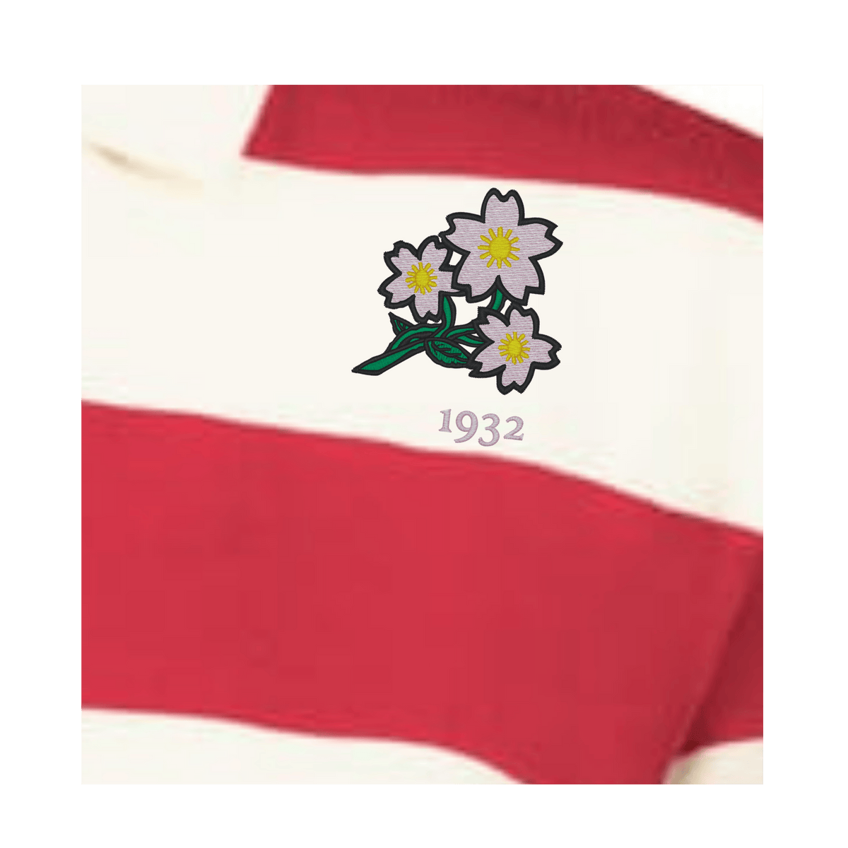 A close-up of the EMB Augusta Women's Vintage Japan Prep Street Rugby Crop, featuring red and white stripes, embroidered with three white flowers above the number "1932.