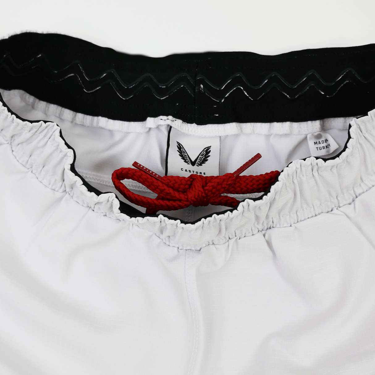 Close-up of the waistband on the Castore Women's USA Rugby 22/23 RWC Home Pro Short, showing a black inner band, red drawstring, and manufacturer tag.