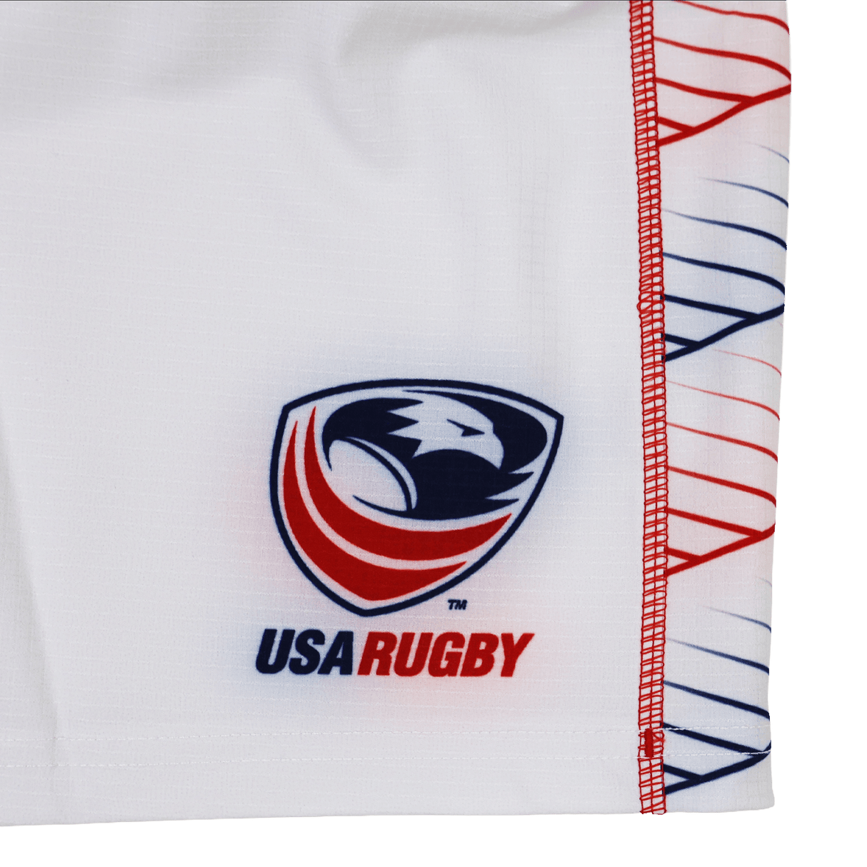 The Women's USA Rugby 22/23 RWC Home Pro Short by Castore features a white base, the USA Rugby eagle head logo with red, white, and blue accents, plus a geometric red and blue line pattern on the side.