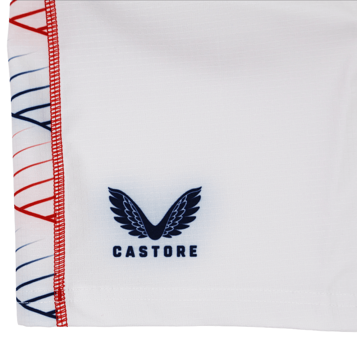 Close-up of the Women's USA Rugby 22/23 RWC Home Pro Short by Castore, showing white fabric with the Castore logo in navy blue and decorative red and blue stitching along the edge.