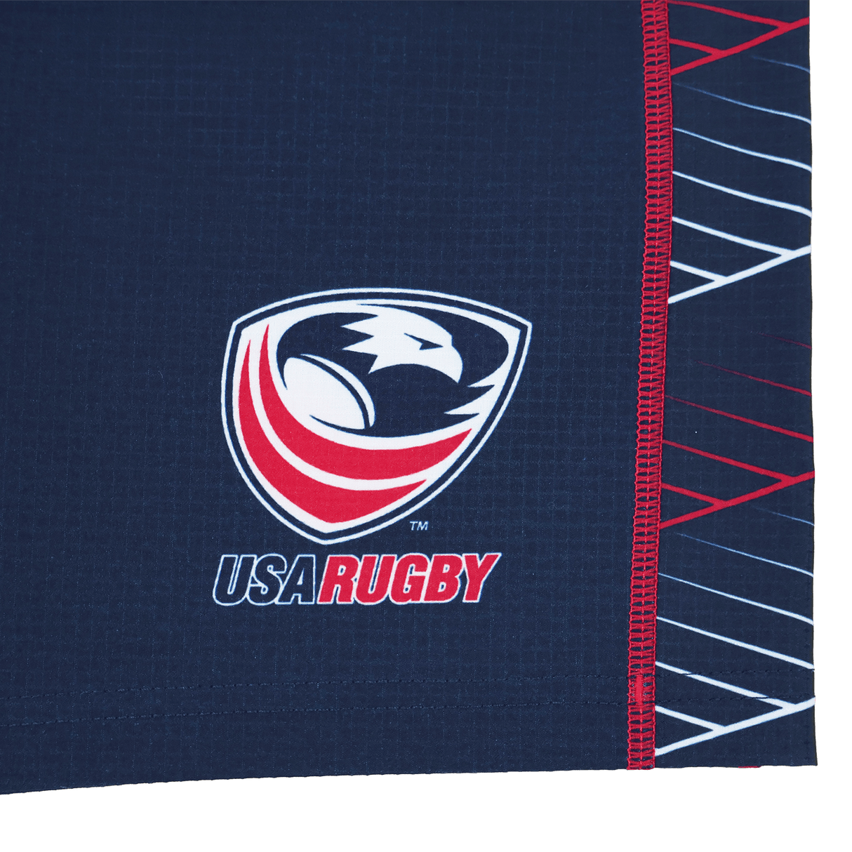 Close-up of the USA Rugby eagle and shield logo with "USA RUGBY" text on a dark blue Castore fabric with red and white accents, featured on the Women's USA Rugby 22/23 7s RWC Away Pro Short by Castore.
