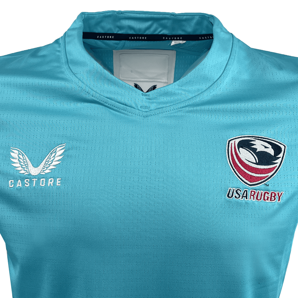 The Women's USA Rugby 24/25 Pro Training Jersey by Castore features a blue design with the Castore logo on the left and the USA Rugby emblem on the right, ideal for women's rugby training.