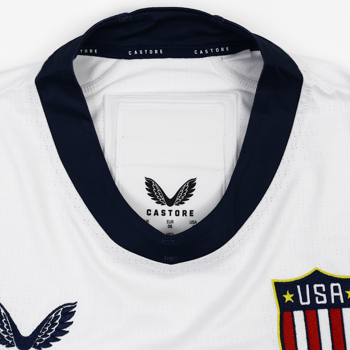 Close-up of the collar on the Women's USA Rugby 7s Olympic Pro Away Jersey by Castore, showing navy trim, the Castore logo, and a "USA" shield crest on the chest.