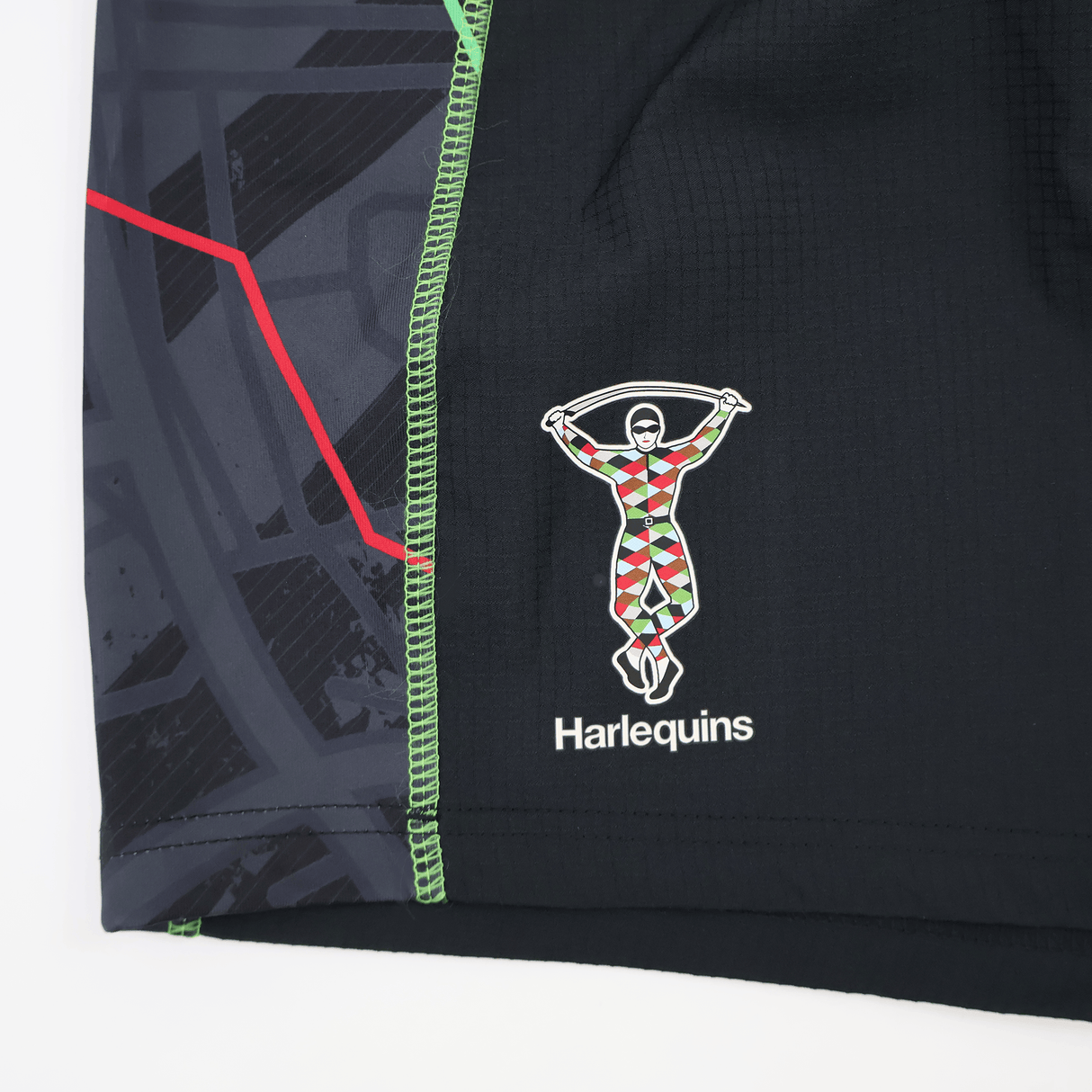 Close-up of the Harlequins 22/23 3rd Pro Short by Castore, highlighting bold red, green, and black geometric patterns along with the Castore logo and text.