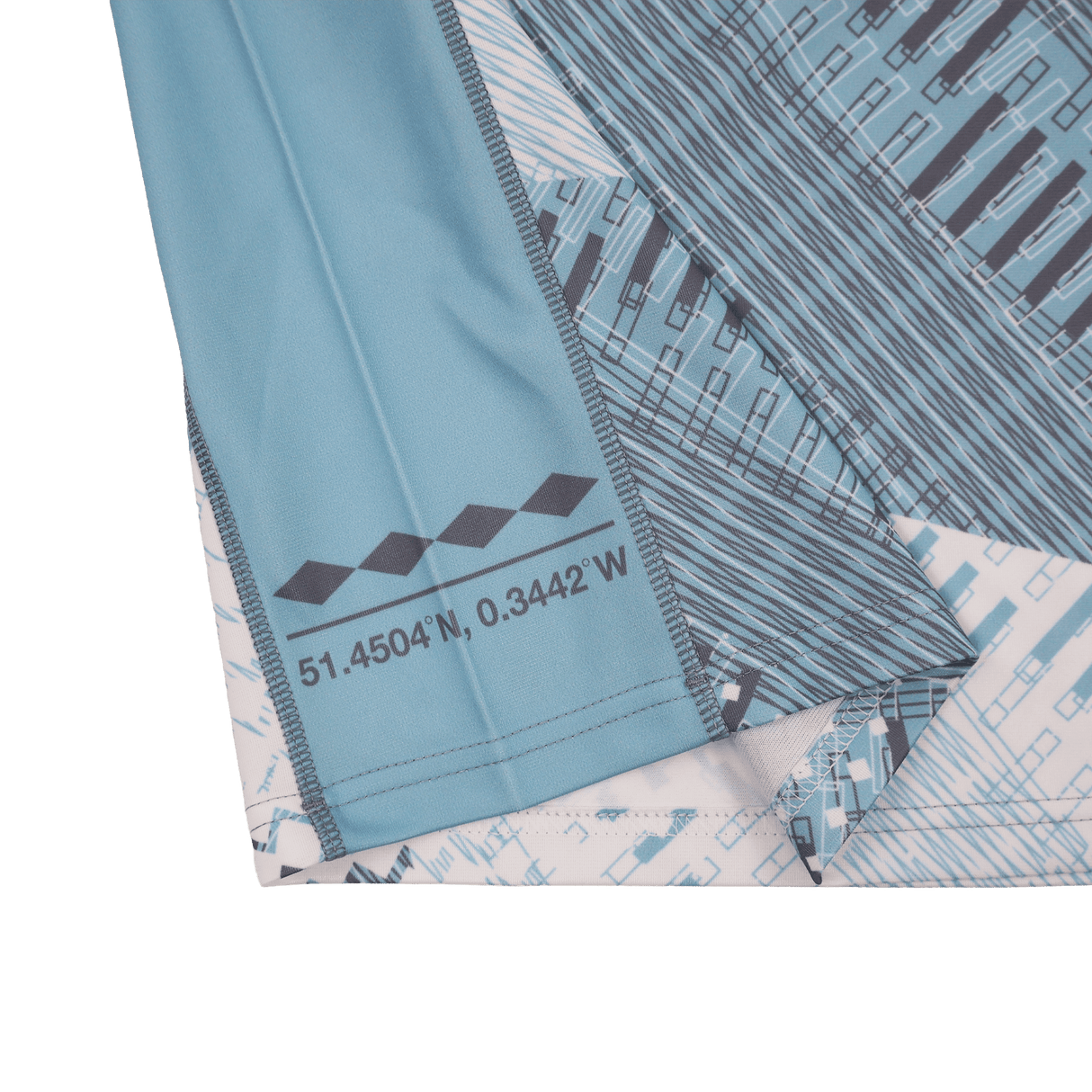 Close-up of the Castore Harlequins 22/23 Replica Away Jersey, featuring a blue pattern, printed coordinates "51.4504°N, 0.3442°W" near the hem, and a small geometric design.