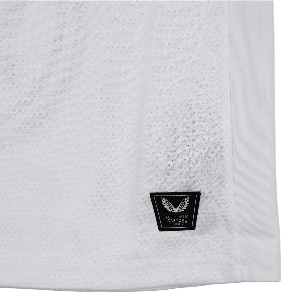 Close-up of the lower part of the Ulster 25/26 Pro Home Jersey by Castore, showing a black "Authentic Fabrique" patch with a winged logo near the hem, designed in Castore's signature performance style.