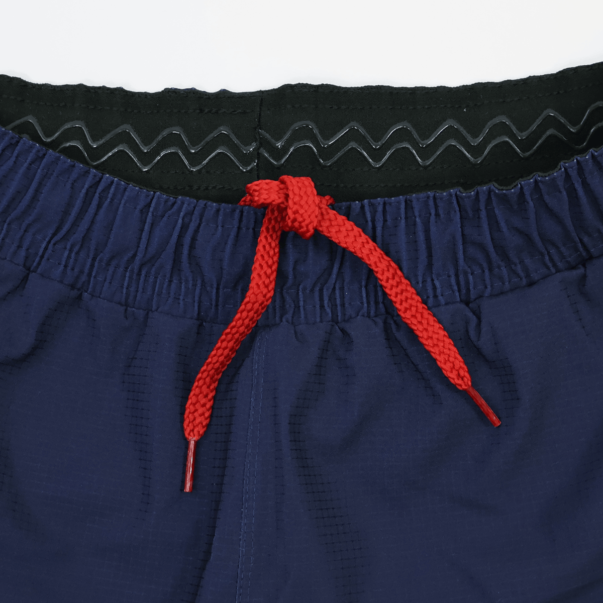 Close-up of the waistband of Castore USA Rugby 22/23 Pro Home Shorts, showing a black inner lining and a red drawstring tied in a knot.