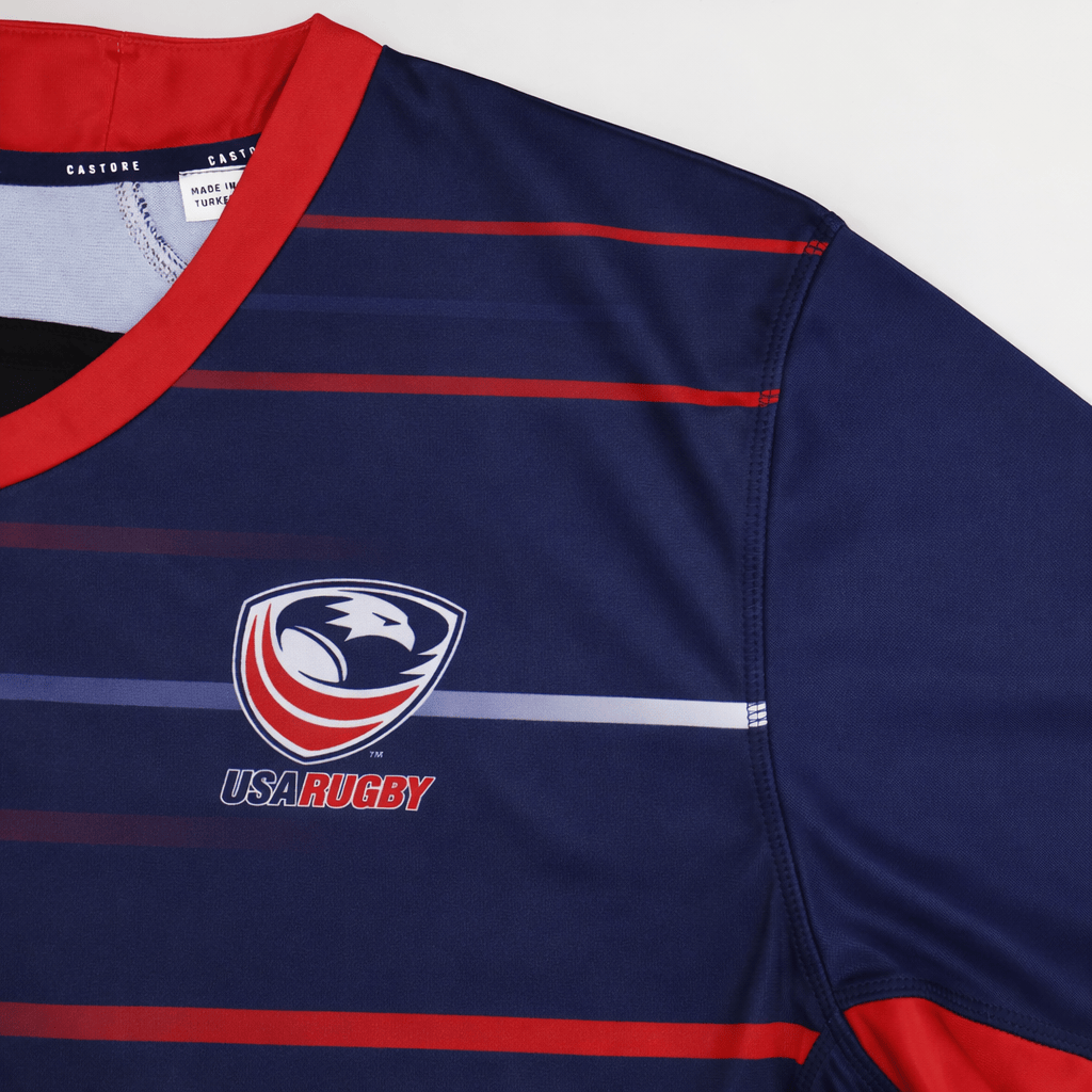 Close-up of the USA Rugby 22/23 Pro Away Jersey by Castore in navy blue with red and light blue stripes, showcasing the USA Rugby logo on the chest.