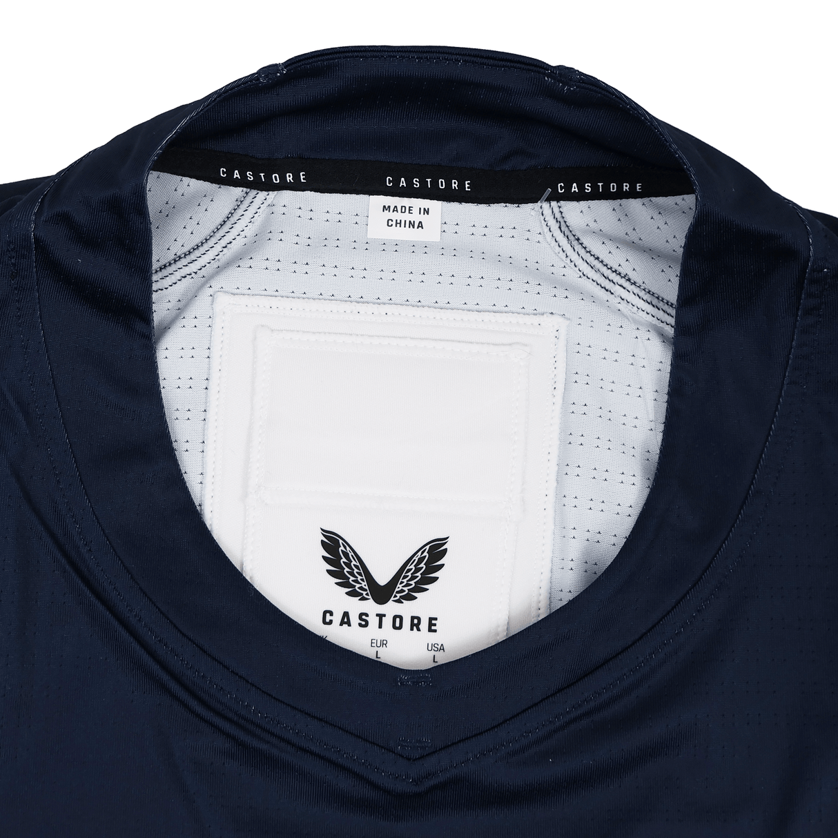 Close-up of the collar on the USA Rugby 23/24 Training Jersey by Castore, featuring "Castore" branding, label details like "Made in China," the black winged logo, and a tribute to USA Rugby.