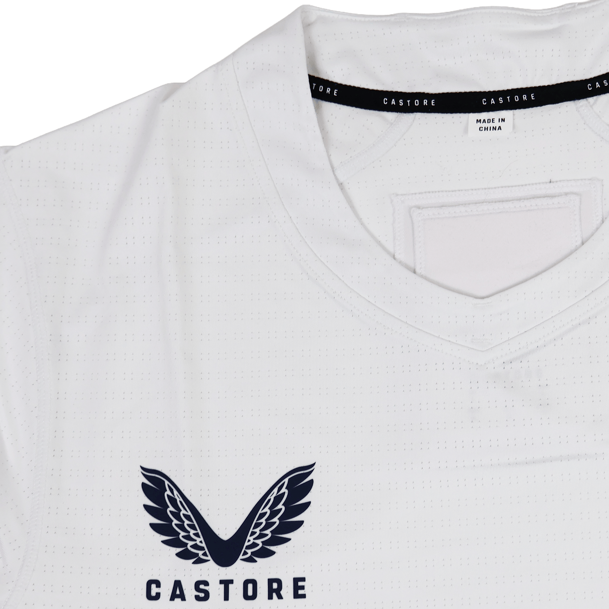 Close-up of the USA Rugby 23/24 Training Jersey by Castore, a white training top with a V-neck collar, Castore’s winged logo on the chest, and a "Made in China" label inside the neckline.