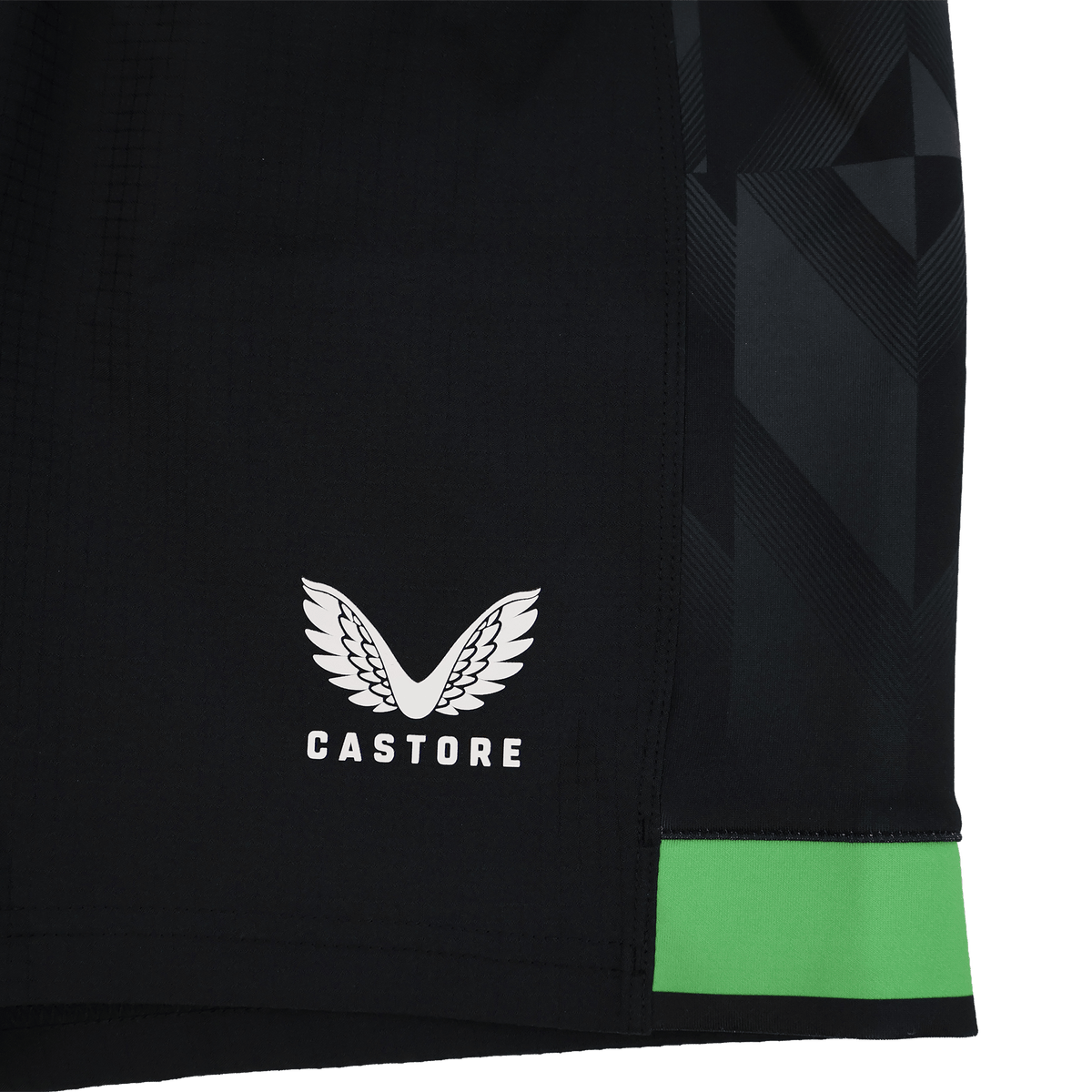 Close-up of the Harlequins 23/24 Home Shorts by Castore: black rugby shorts with a white winged Castore logo, a green band near the hem, and a geometric side pattern—part of Castore’s official collection.