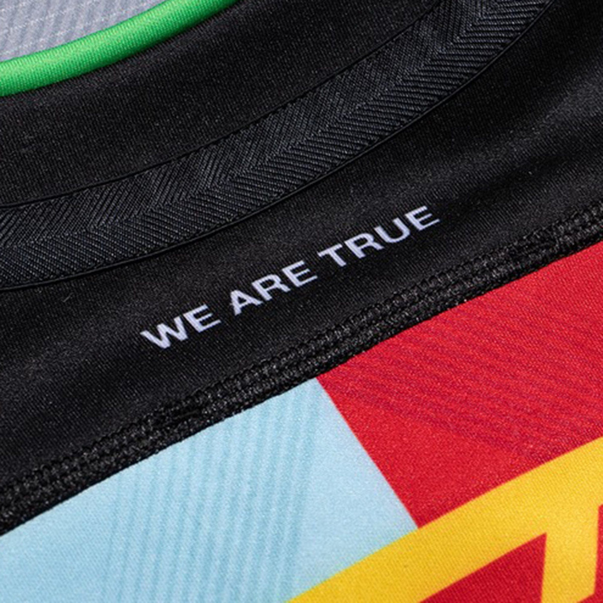 Close-up of the Harlequins 23/24 Pro Home Jersey by Castore, featuring a multicolored design and "WE ARE TRUE" printed in white on the black collar.