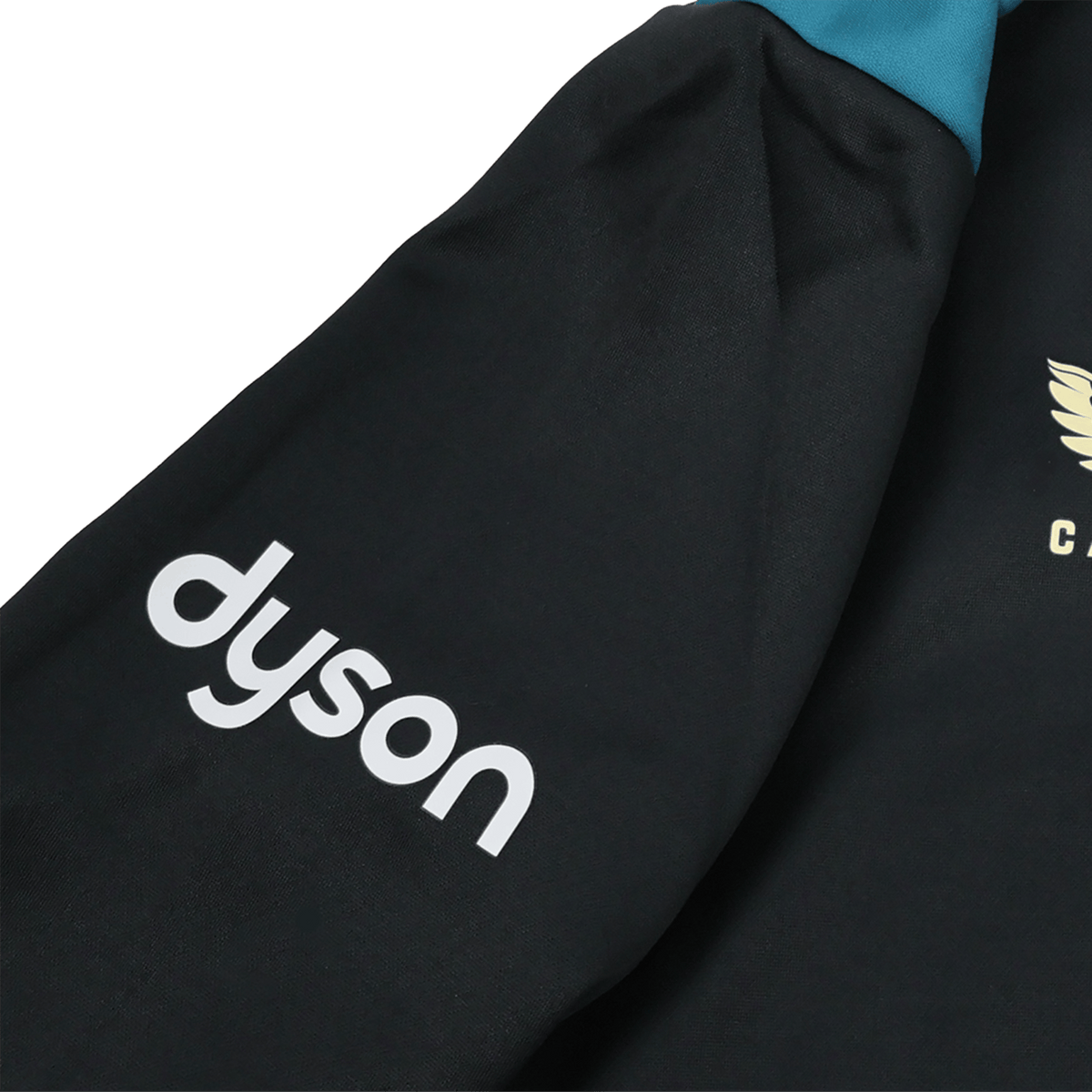 A close-up of the Bath 23/24 Full Zip Hoodie by Castore shows a black sleeve with the white "dyson" logo and a gold winged emblem—ideal fan gear from Castore for rugby supporters.
