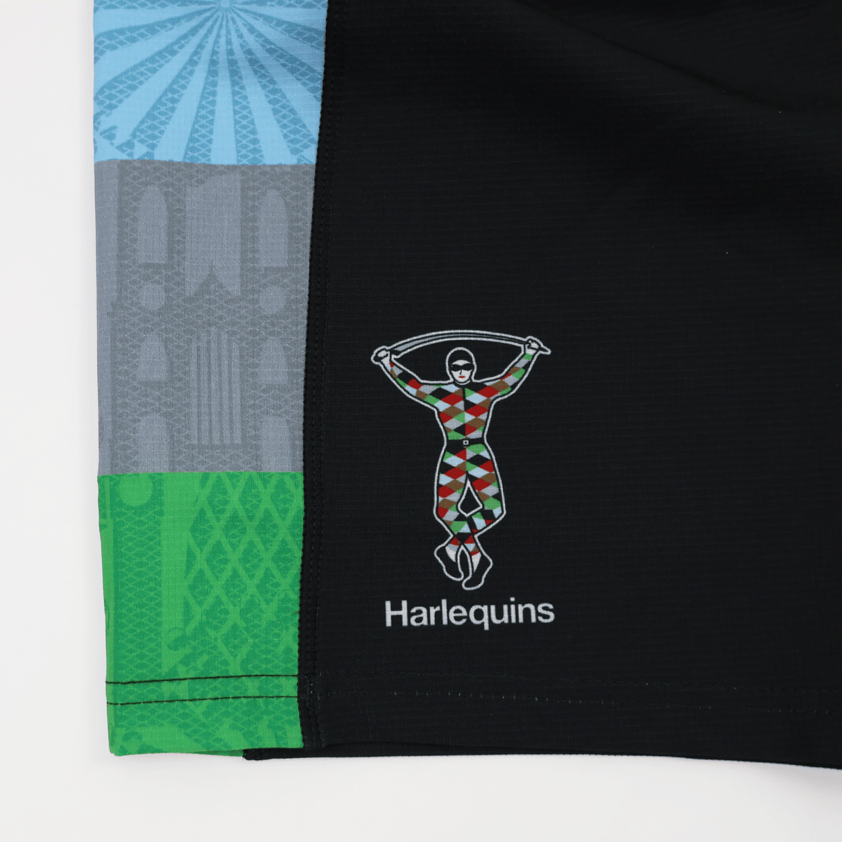 Close-up of the Harlequins 24/25 Pro Home Short by Castore, featuring the rugby teamwear logo with a colorful harlequin figure holding a baton and "Harlequins" text, proudly showcasing club spirit.