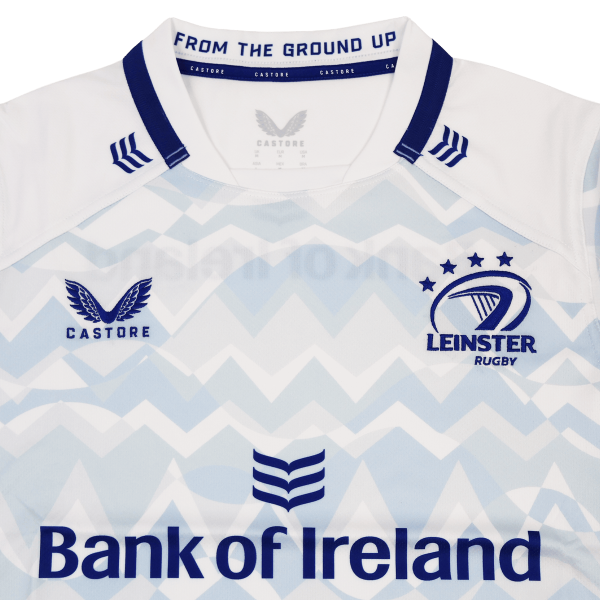 A close-up of the Leinster 24/25 Replica Away Jersey by Castore highlights the Leinster Rugby crest and Bank of Ireland sponsor on a light blue and white zigzag design.