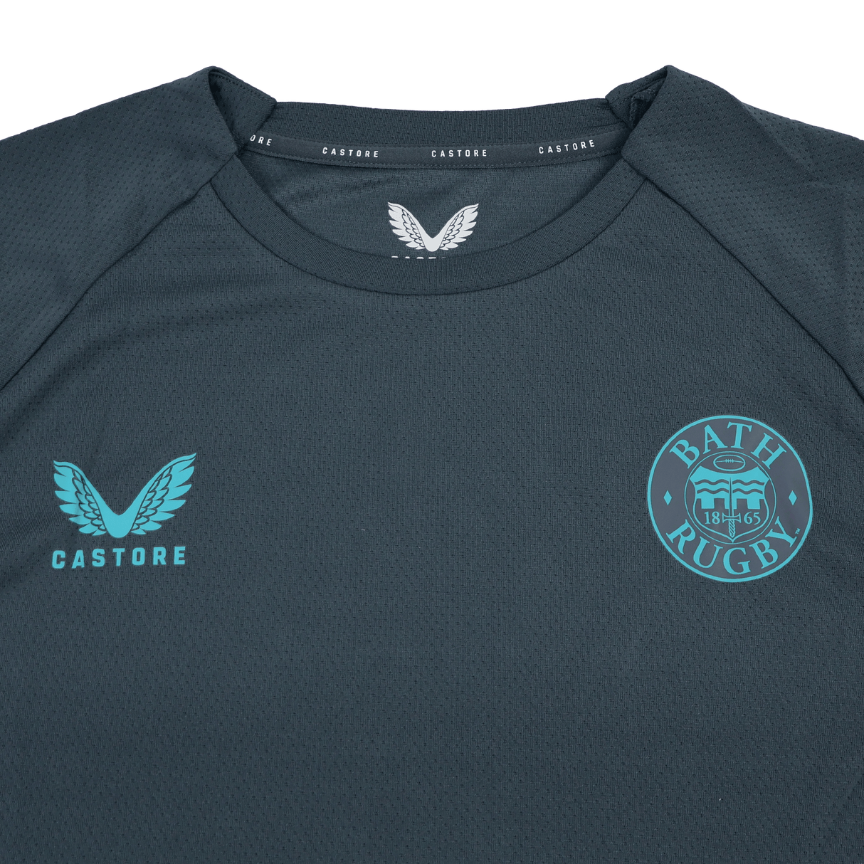 The Bath 24/25 Pro Players Long Sleeve Tee by Castore is a dark gray top featuring the Castore logo on the left chest and Bath Rugby club crest on the right—ideal as a training or casual shirt.