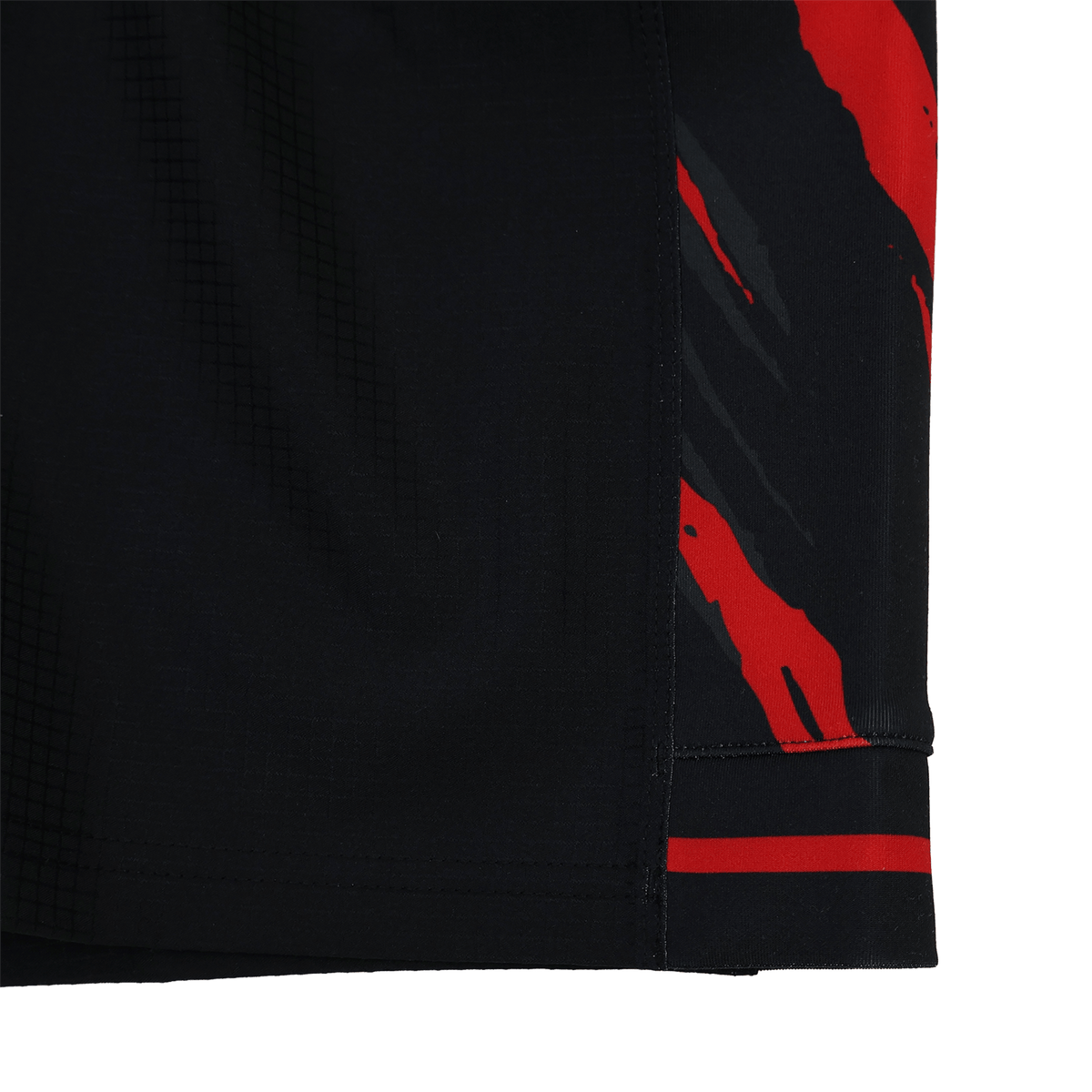 Close-up of Saracens 23/24 Pro Home Shorts by Castore, showcasing black fabric with red and gray abstract streaks along the edge and detailed hem stitching.