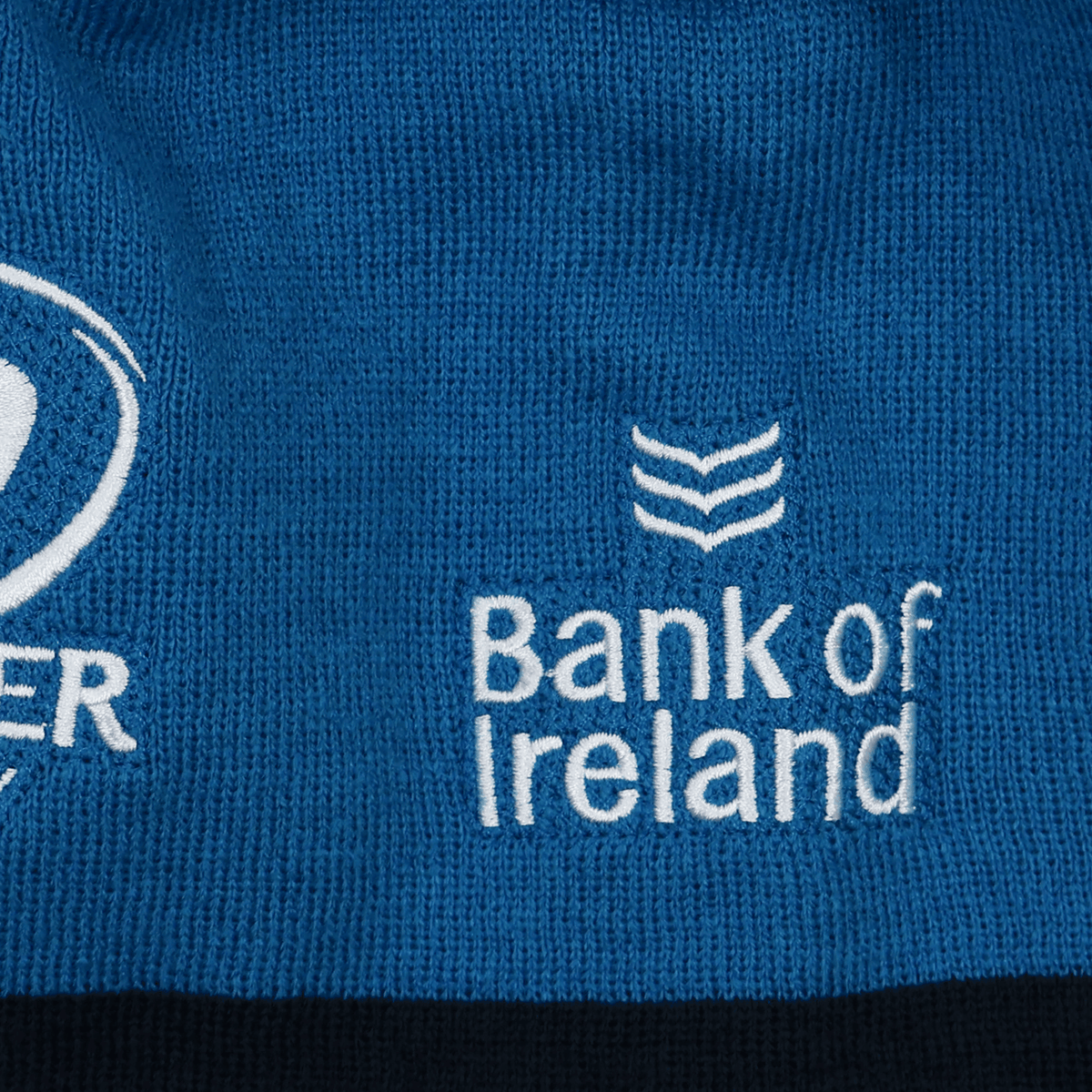 Close-up of blue fabric on the Leinster 24/25 Beanie by Castore, showing the embroidered "Bank of Ireland" logo and part of another logo in white thread.